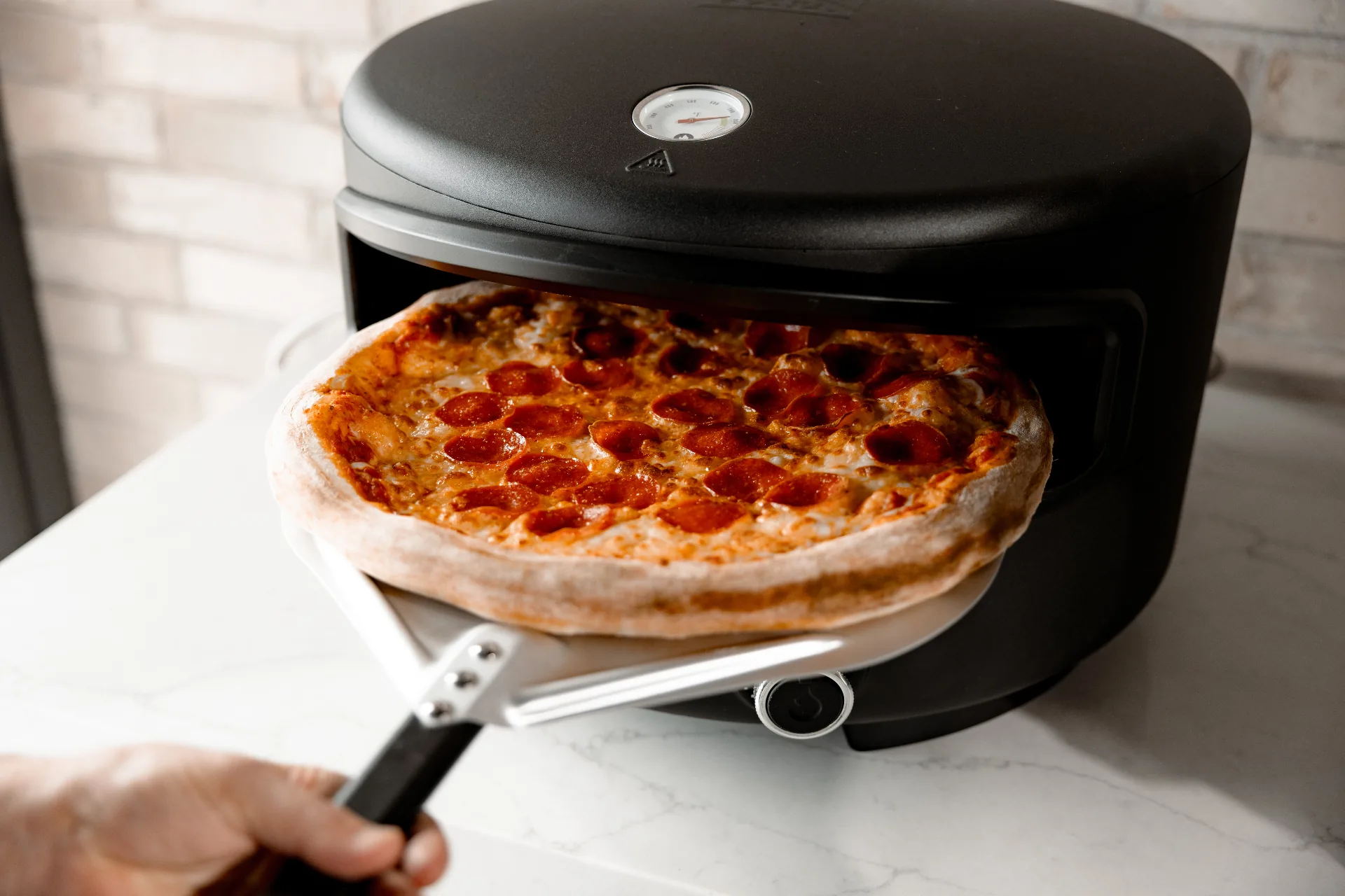 A pepperoni pizza coming out of the Festa oven